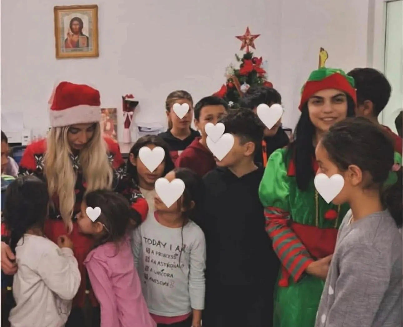 Moș Crăciun și un spiriduș printre copii, lângă bradul de Crăciun