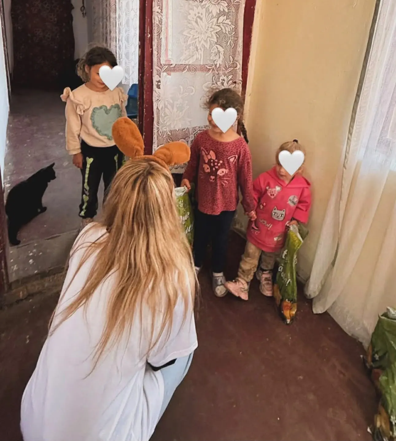 O voluntară cu urechi de iepuraș dă pachete de Paște unor fetițe acasă